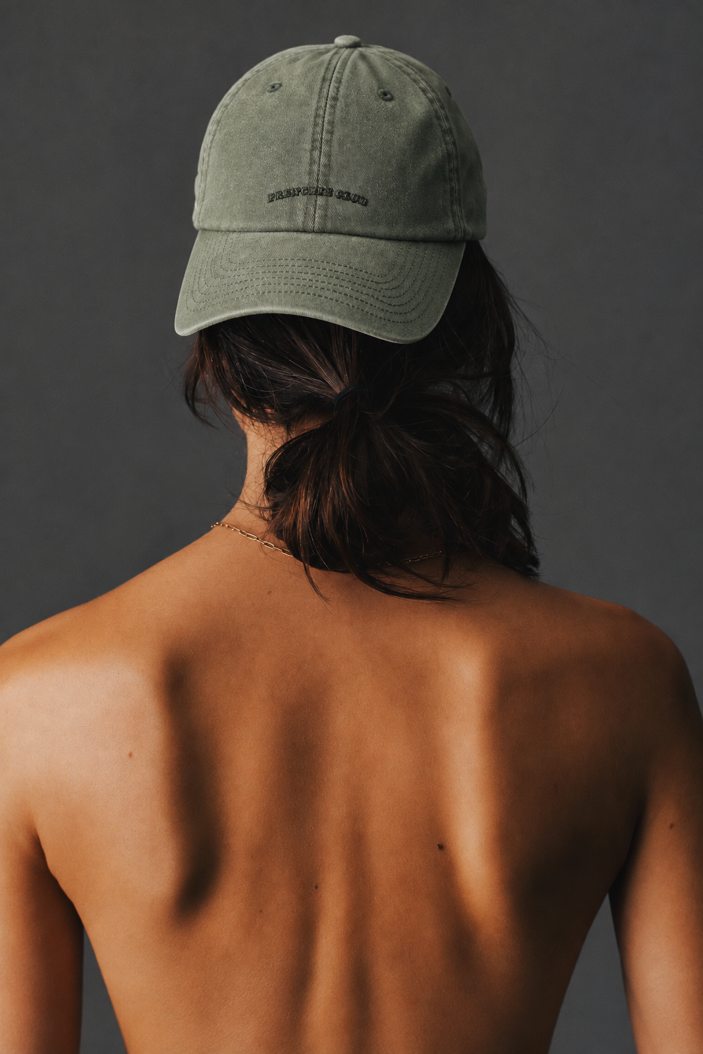 Olive Frenchie Club cap styled backwards with a low bun
